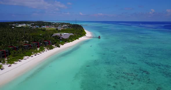 Natural fly over clean view of a white sandy paradise beach and blue sea background in 4K alt