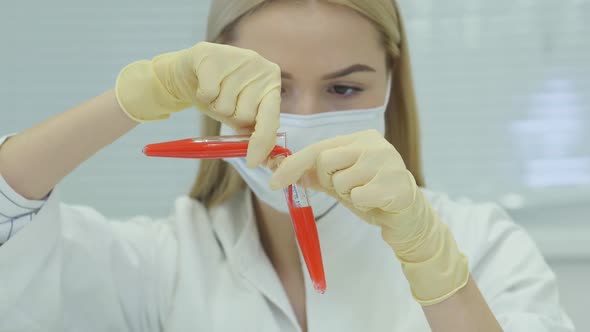 Scientist Looking In A Test Tube Overflowing A Red Liquid