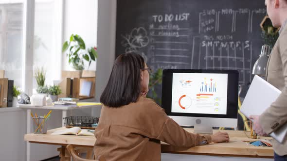 Businesswoman Discussing Finances with Male Colleague in Office alt
