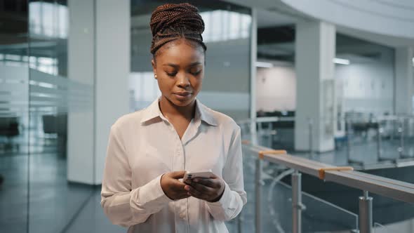 African Serious Focused Female Office Manager Woman Boss Leader with Modern Smartphone in Office alt