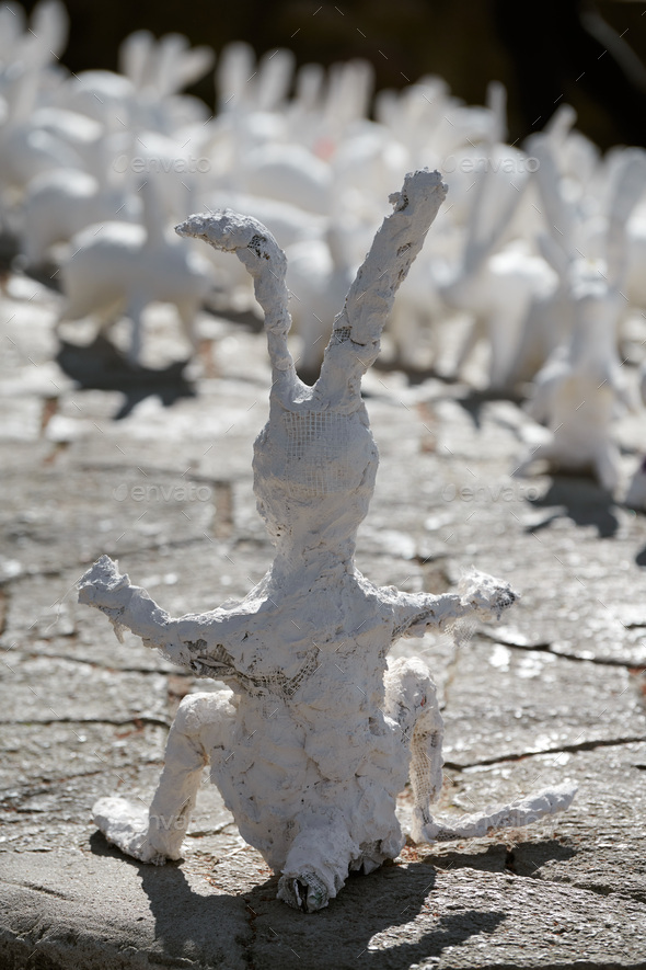 Big white rabbit statue made of plaster back view, outdoor art exhibition, artificial strange hare