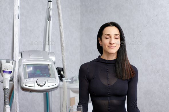 woman in a black suit for LPG massage sits with closed eyes before LPG massage. Anti-cellulite body