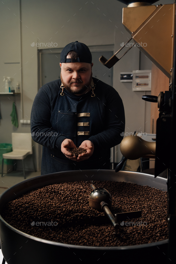 Man smelling coffee beans from cooling tray - Stock Photo - Images