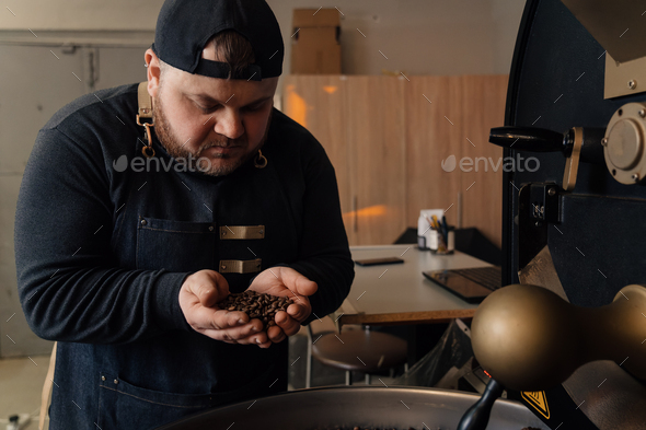 Man smelling coffee beans from cooling tray - Stock Photo - Images