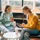 Two cheerful laughing women friends in a coffee shop communicate and chat on the phone. - PhotoDune Item for Sale