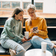 Two modern confident women friends in a coffee shop communicate and chat on the phone. - PhotoDune Item for Sale