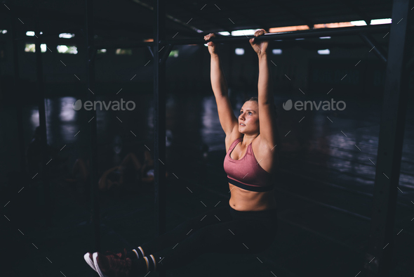 Muscular female athlete training body muscles while doing pull ups in ...