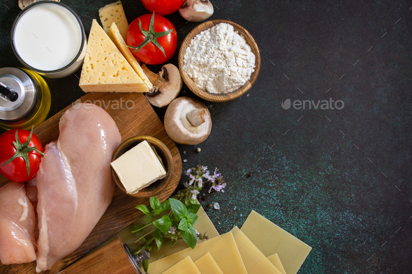 Ingredients for cooking lasagna with chicken and mushrooms on a dark stone background.  - Stock Photo - Images