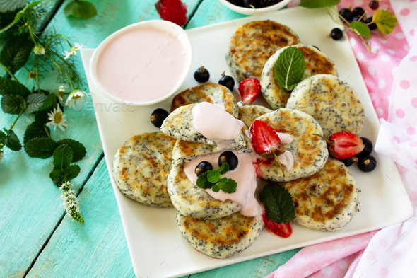 Homemade cottage cheese pancakes with poppy seeds, sour cream sauce with strawberries.  - Stock Photo - Images
