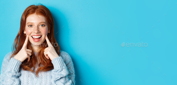 Close-up of cheerful teenage girl with red hair and freckles, poking ...
