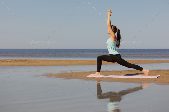 yoga, Warrior Pose, sporty woman does warm-up on seashore in morning. - Stock Photo - Images