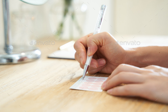 A woman writes the date on her loyalty card at a beauty salon