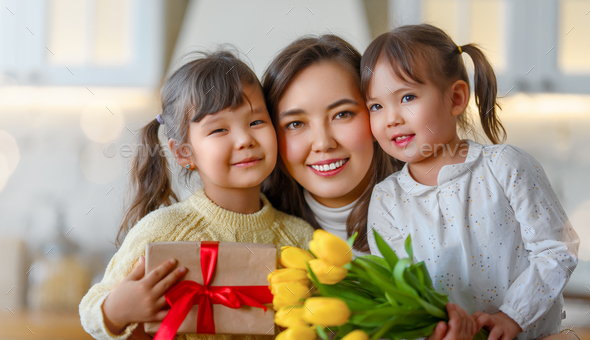 Daughters giving mother bouquet of flowers. - Stock Photo - Images