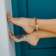 beautiful woman&#39;s feet with tattoo and accessory closed to white wall - PhotoDune Item for Sale