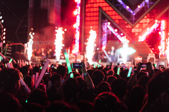 Crowd of concert stage lights and people fan audience silhouette raising hands or glow stick holding