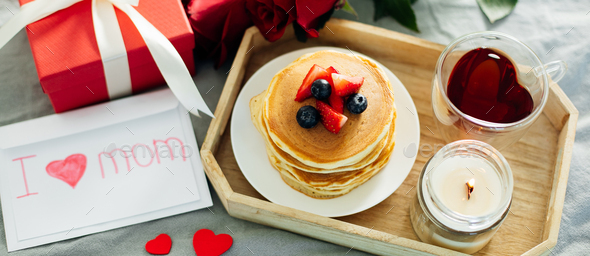 Banner image for desing web page. Mother's Day concept. Pancakes with berry, tea cup, burning candle - Stock Photo - Images