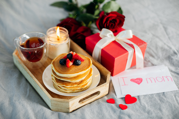 Holiday breakfast or brunch set served on gray bed with flowers, gift box and candle. - Stock Photo - Images