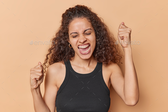 Positive Overjoyed Afro American Woman Celebrates Success Exclaims Gladfully Clenches Fists 8996