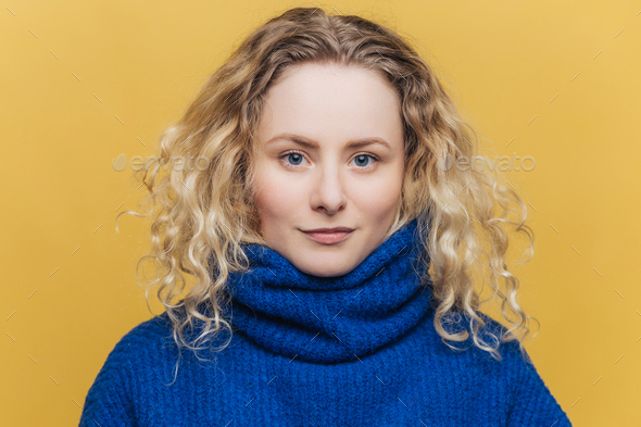serious blue eyed female wears blue warm sweater, looks confidently at camera - Stock Photo - Images