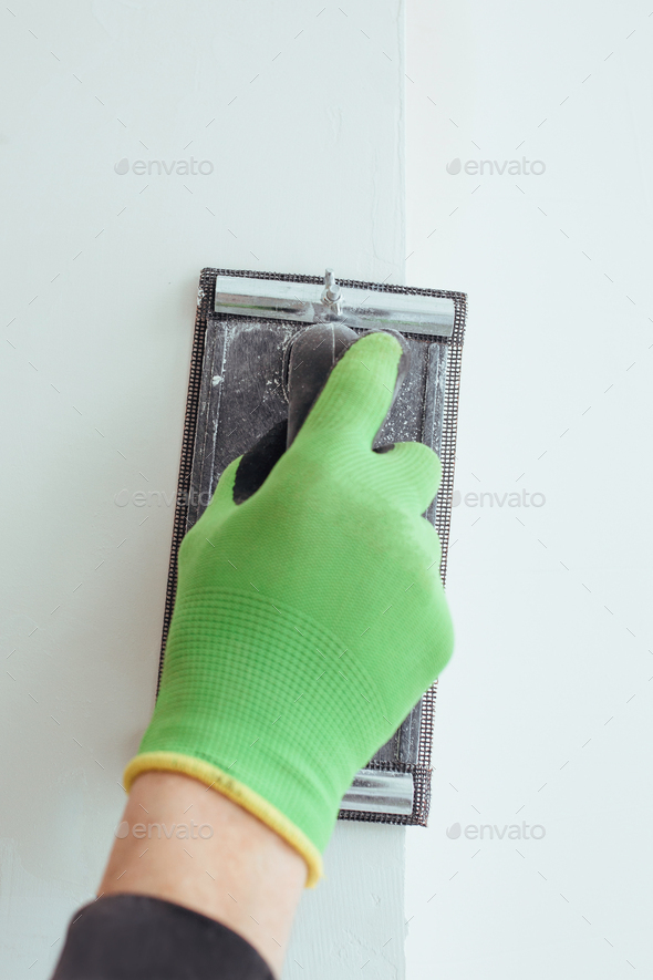 a man\'s hand in a green glove is grinding the wall