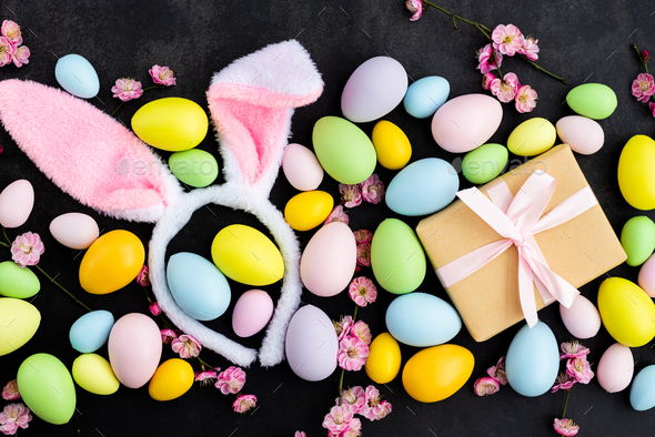 Stylish background with colorful easter eggs on dark concrete background with blooming branches - Stock Photo - Images