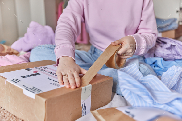 Cropped shot of unrecognizable woman prepares parcel for client at home packs paper box with skotch - Stock Photo - Images