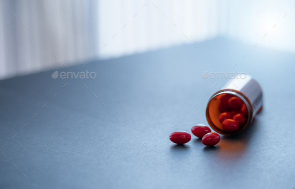Red capsule pills and brown plastic drug bottle. Codeine and guaifenesin capsule pills to relieve  - Stock Photo - Images