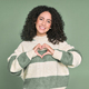 Young happy latin woman showing heart with hands isolated on green. - PhotoDune Item for Sale