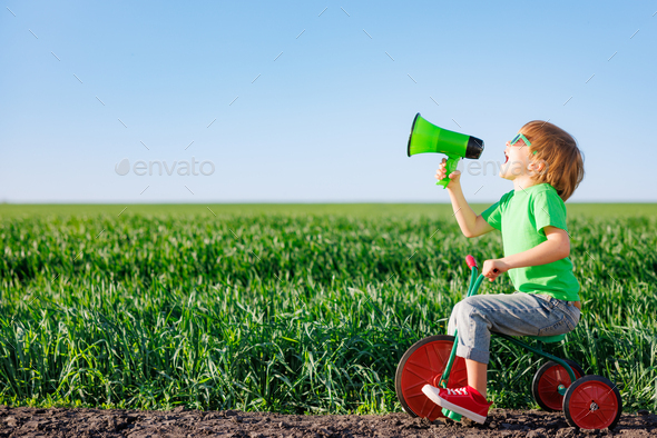 Child shouting through loudspeaker against blue summer sky - Stock Photo - Images
