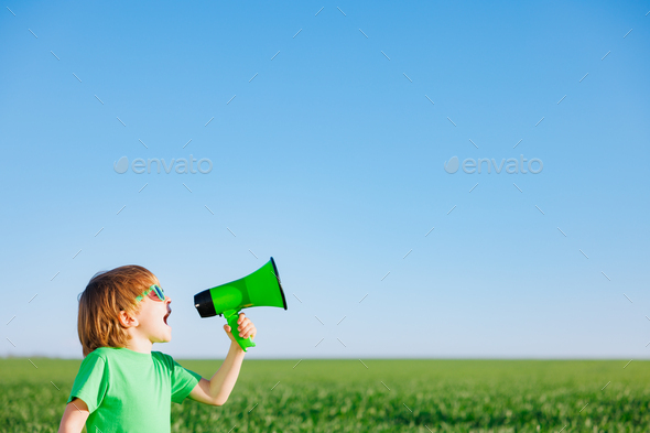 Happy child shouting through loudspeaker against blue summer sky - Stock Photo - Images