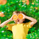 Surprized child holding slices of orange fruit like sunglasses - PhotoDune Item for Sale