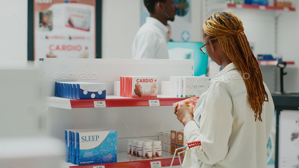 Young woman checking box of pills in medical shop