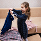 Baby girl choosing clothes from the wardrobe at home on the sofa. - PhotoDune Item for Sale