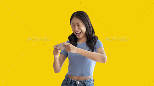 Asian woman playing games on mobile phone and wearing headphones having fun
