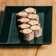Sweet sushi rolls with banana and chocolate on black plate - PhotoDune Item for Sale