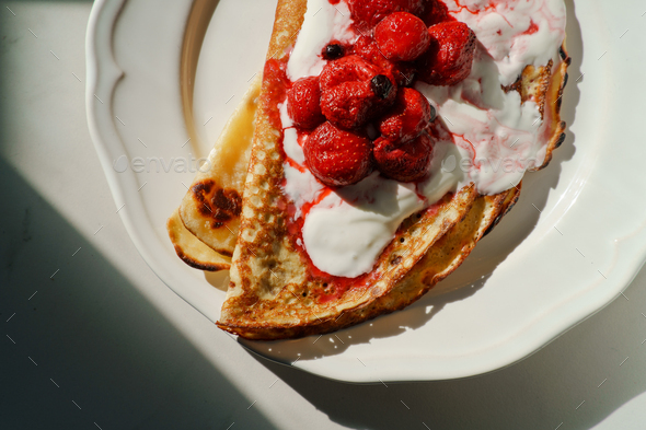 Close up pancakes with sour cream and berries on a plate - Stock Photo - Images
