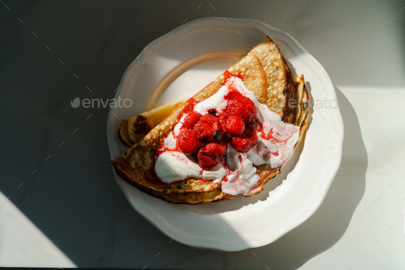 Top view of Pancakes with sour cream and berries on a plate - Stock Photo - Images