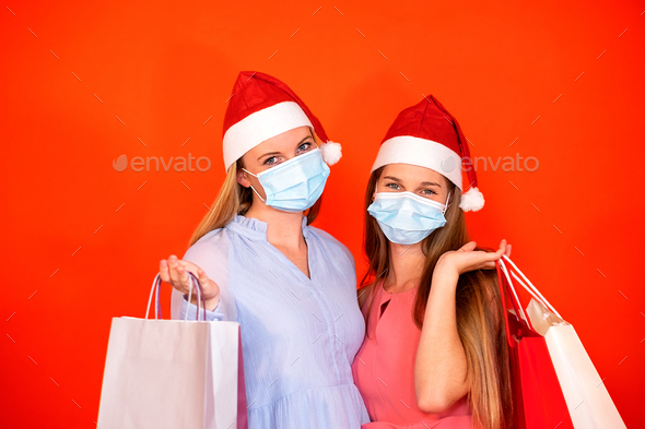female friends wearing surgical mask and Christmas hat