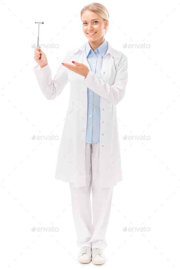 happy young female neurologist pointing at reflex hammer isolated on white