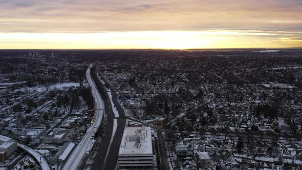 An aerial shot in the suburbs with train tracks and a highway. It was shot at sunrise after a snow s alt