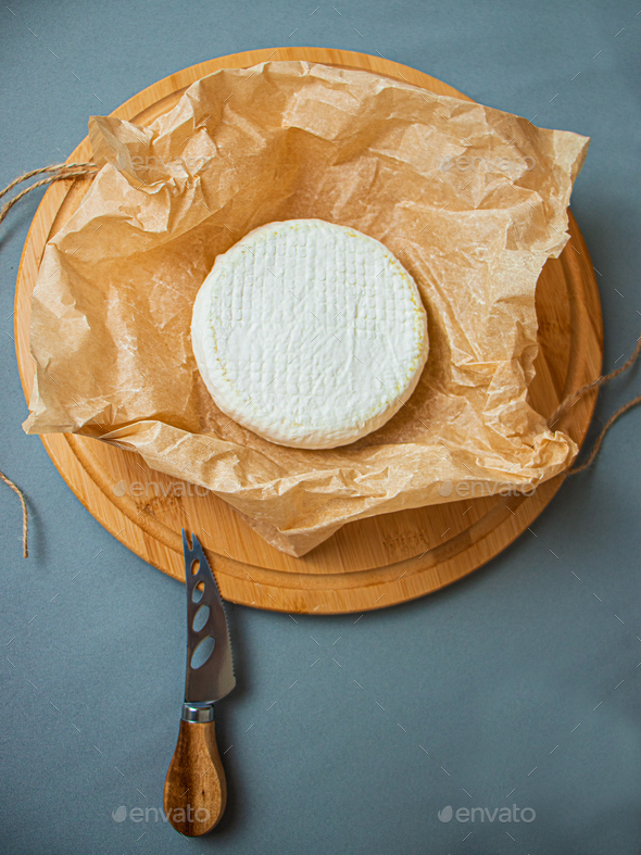 camembert cheese, round brie on kraft paper, cheese, on a cutting board
