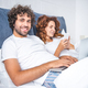 happy young couple using digital devices in bed - PhotoDune Item for Sale