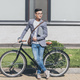 smiling asian man in trendy jacket holding laptop and standing at bicycle - PhotoDune Item for Sale