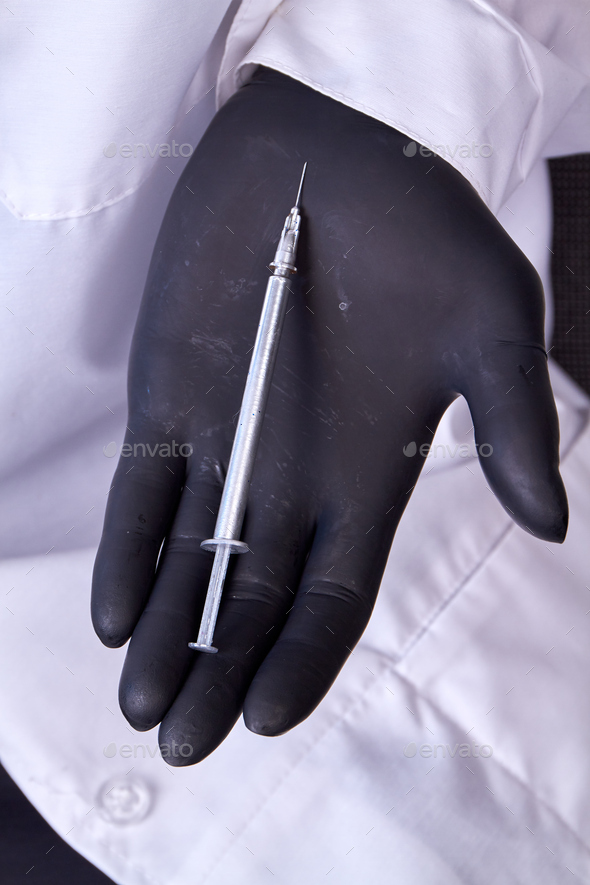 Hand in black glove holding cosmetic syringe. - Stock Photo - Images