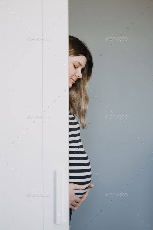 Candid creative portrait of the young pregnant woman in striped t-shirt. Pregnancy, expecting woman - Stock Photo - Images