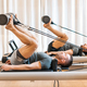 Strong men performing pilates hip mobility exercise on reformer - PhotoDune Item for Sale