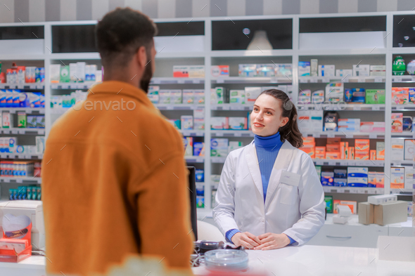 Young pharmacist selling medications to the customer.
