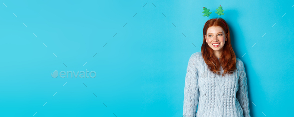 Winter holidays and Christmas sales concept. Cute redhead girl in funny New Year headband smiling