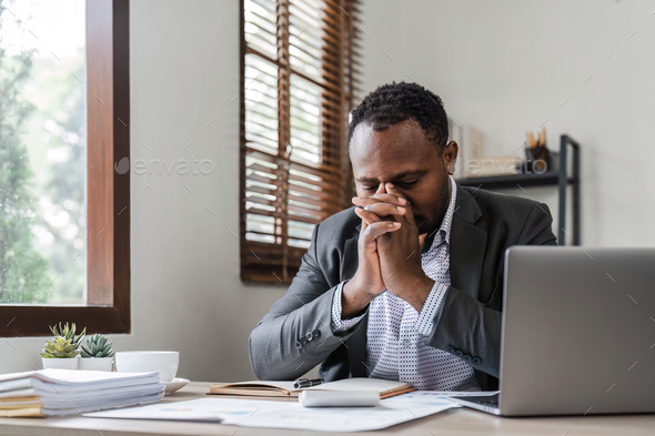 Stressed business man sitting at office workplace. Tired and overworked black man. Young african - Stock Photo - Images