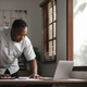 Portrait of handsome African black young business man working on laptop at office desk - PhotoDune Item for Sale